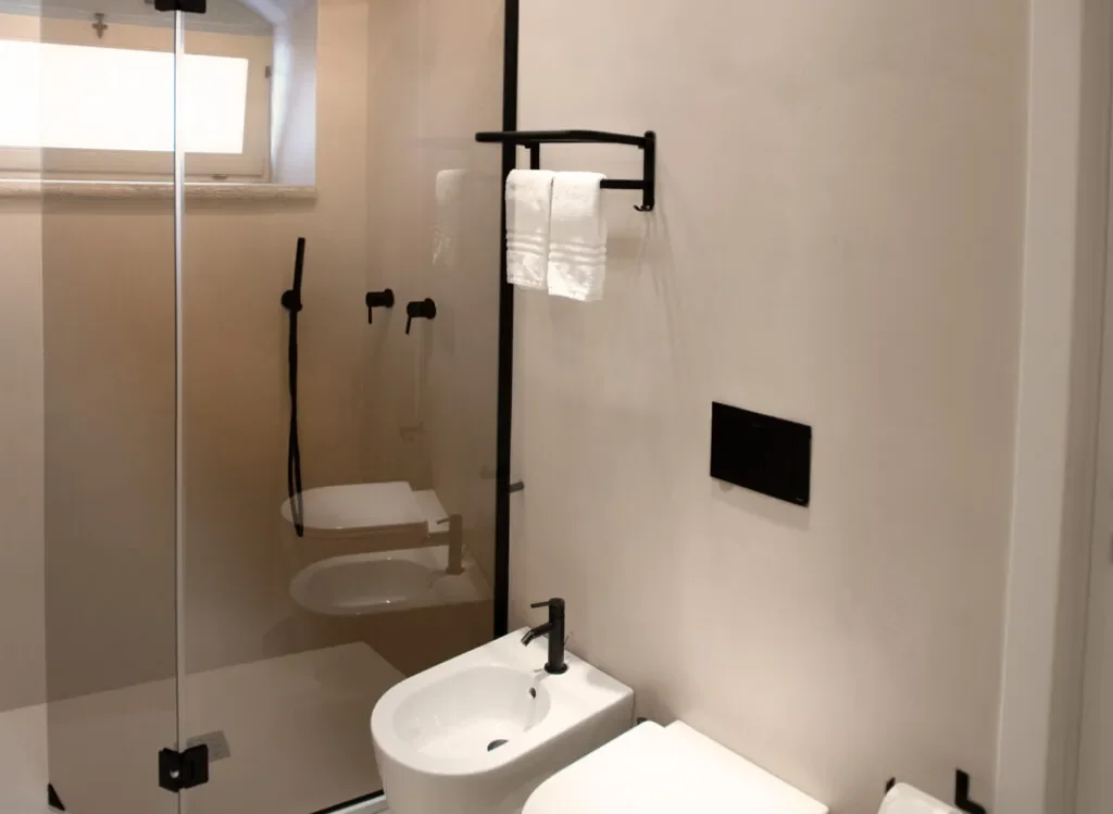 Box doccia in vetro con rubinetteria nera accanto al lavabo