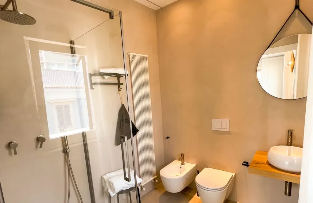 Bagno con lavabo, specchio tondo e box doccia in vetro