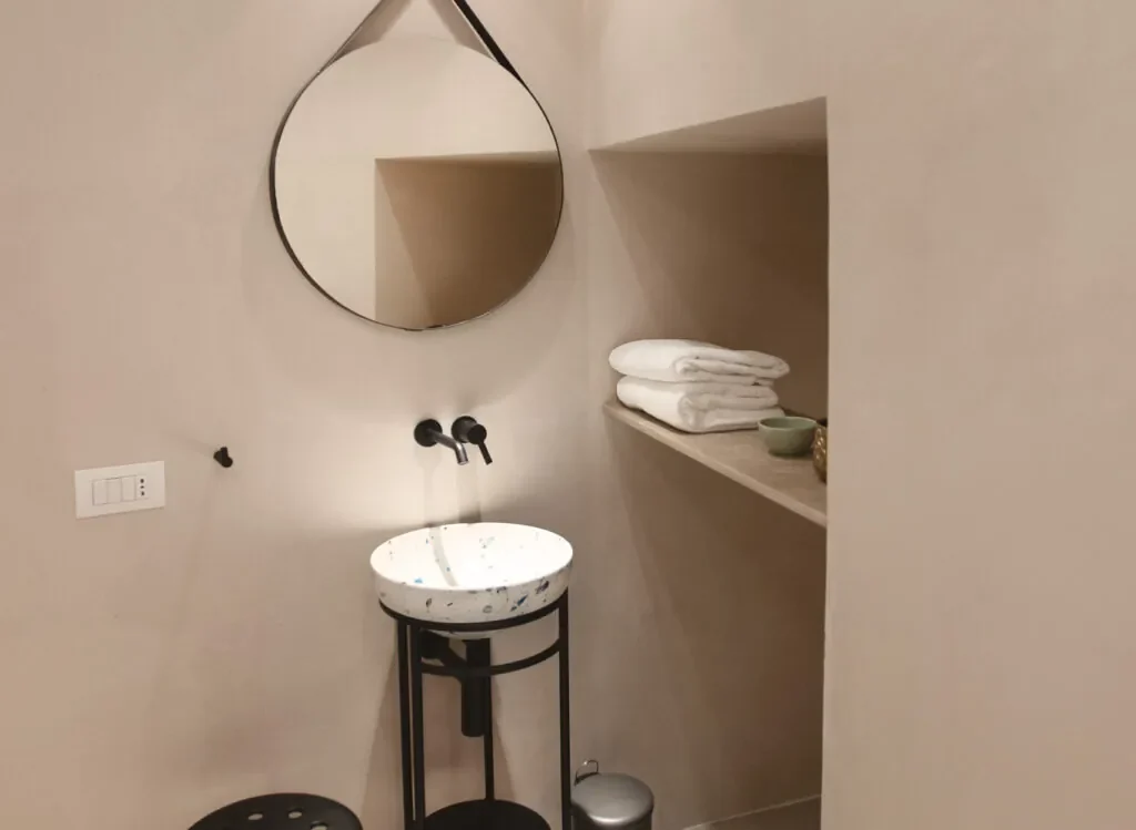 Lavabo su struttura nera e specchio tondo nel bagno