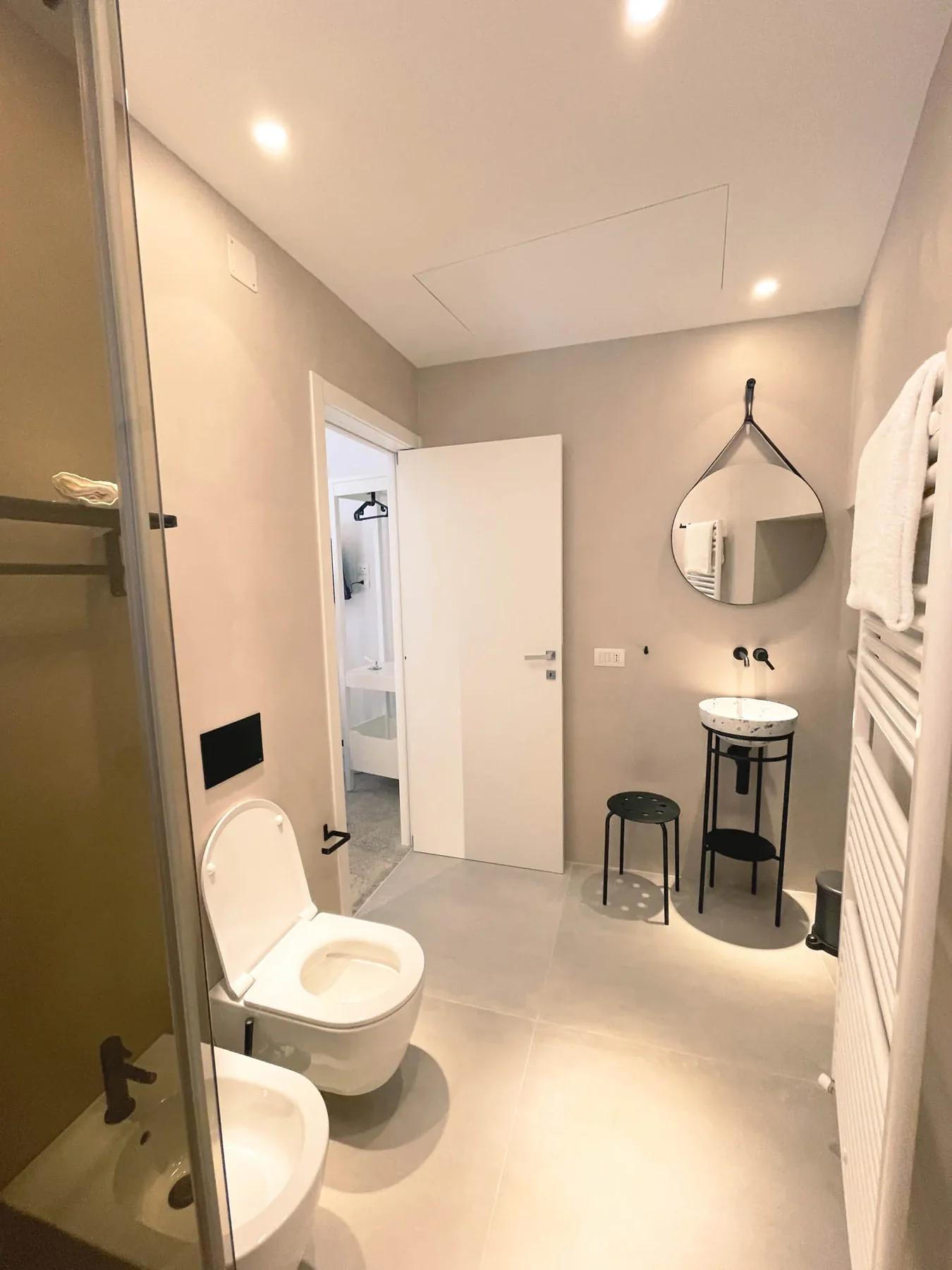 Bagno di Pètra con box doccia e lavabo sotto lo specchio tondo