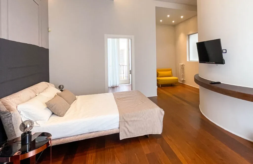 Camera Xylo con letto, parete curva e poltroncina gialla